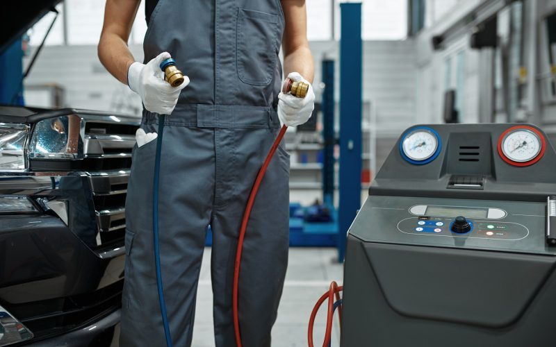 Male mechanic refills air conditioner, car service